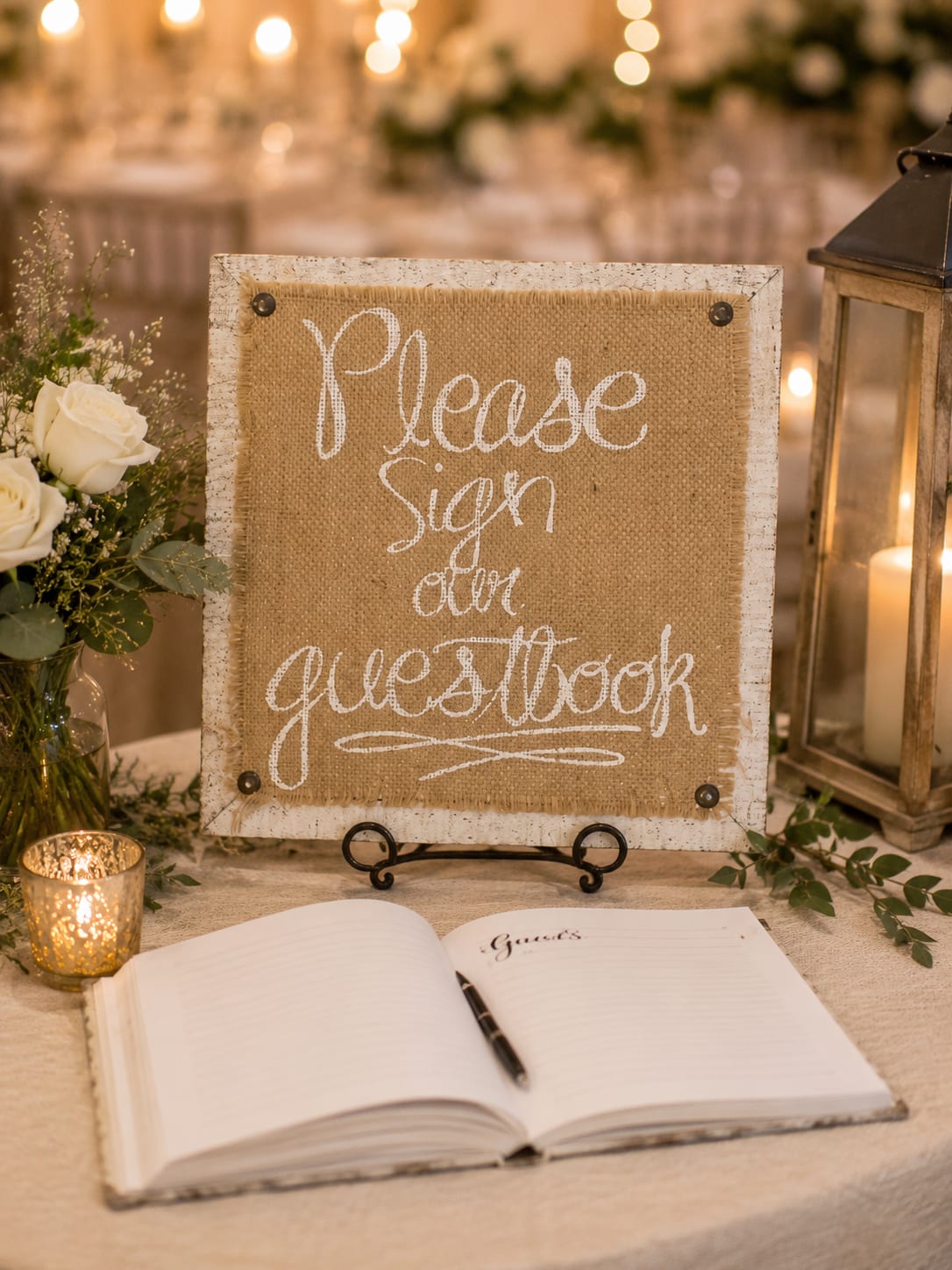 Guest book sign beside white roses and lanterns