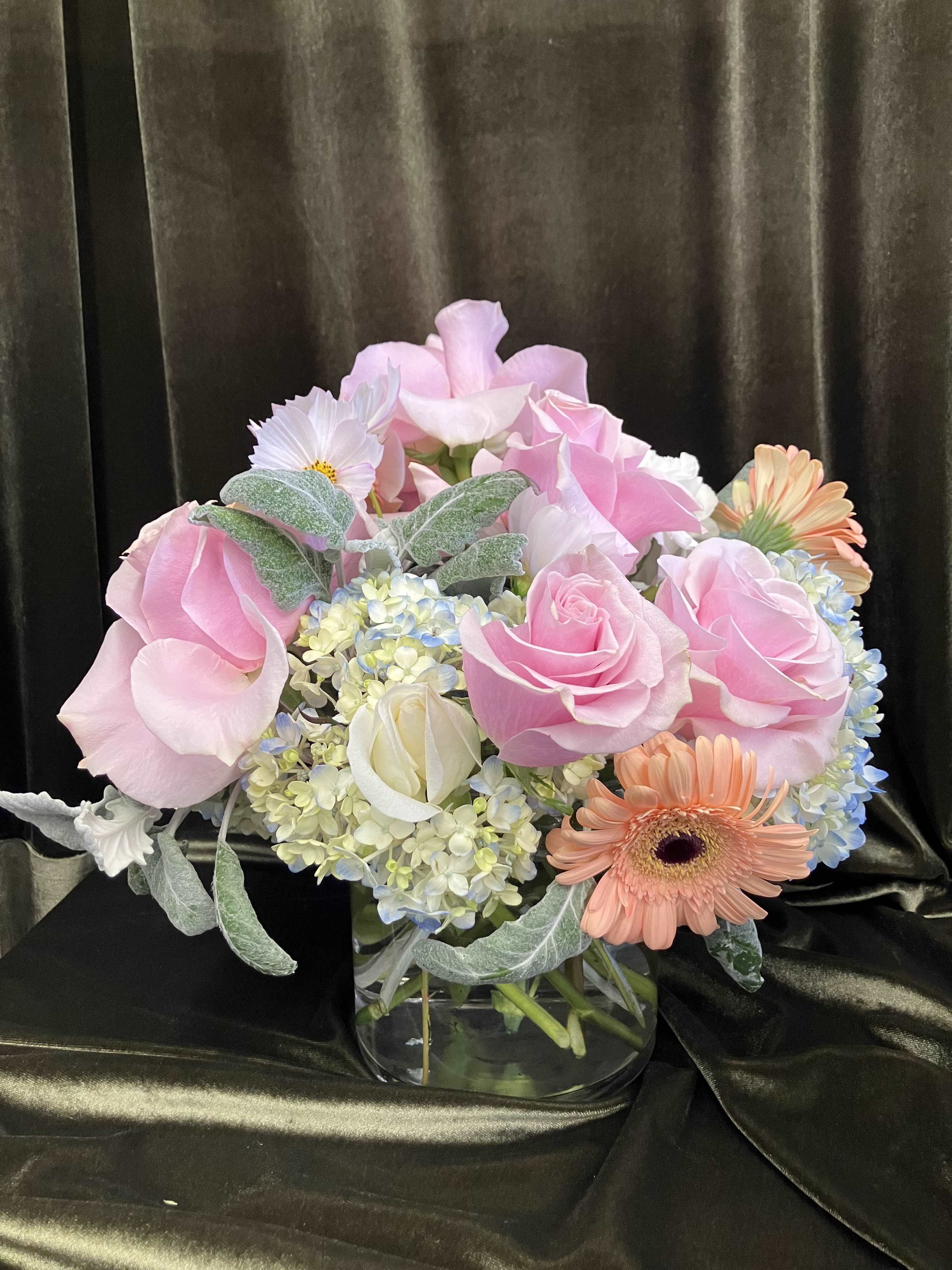 Pink roses and mixed blooms arranged in a clear glass vase