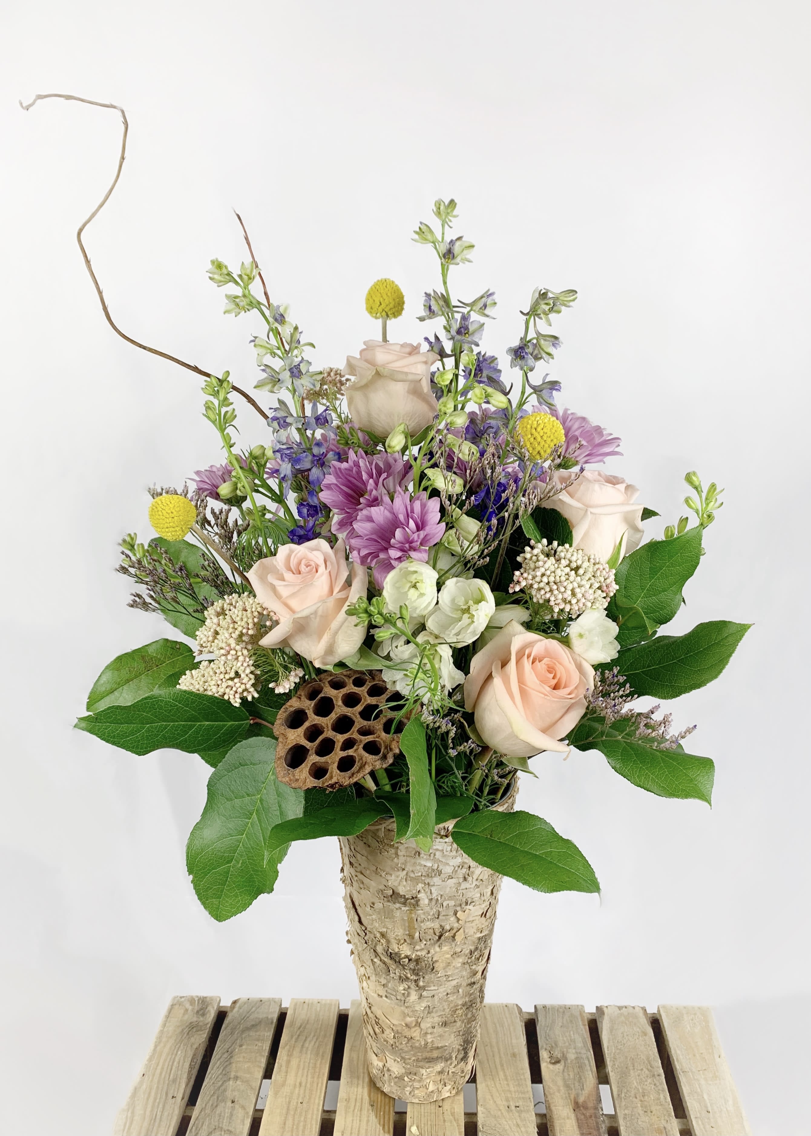 Mixed bouquet in a birch bark vase with pale roses and purple flowers