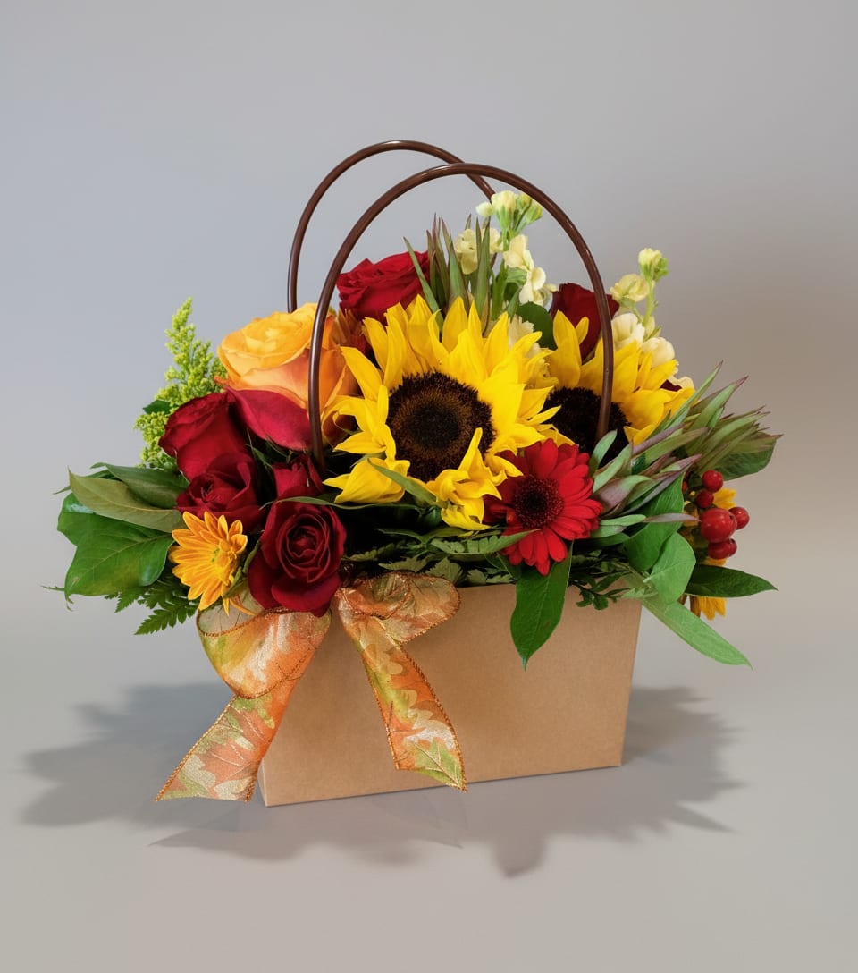 Mixed bouquet with sunflowers, red roses, and a ribboned gift box