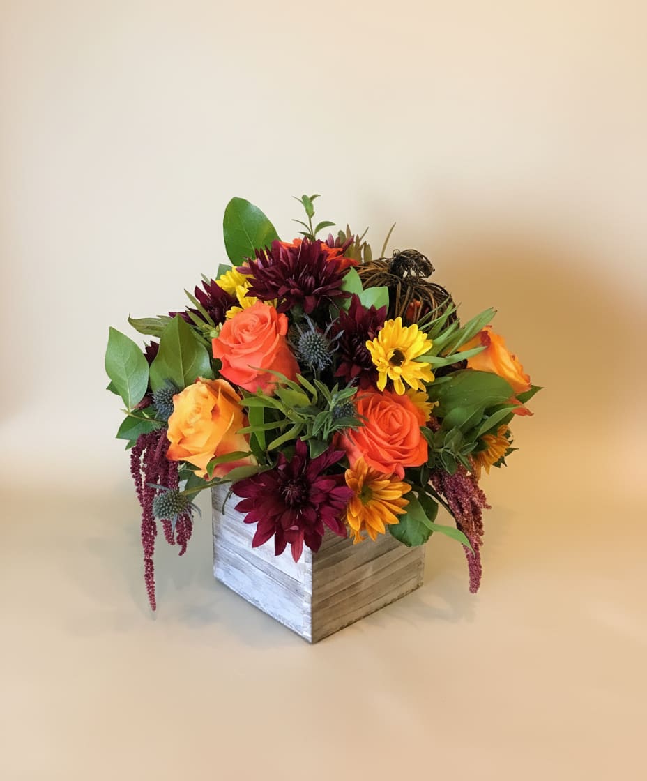 Mixed bouquet of orange and burgundy flowers in a wooden box