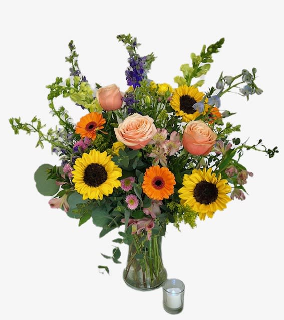 Mixed bouquet with sunflowers, roses, and gerbera daisies in a glass vase