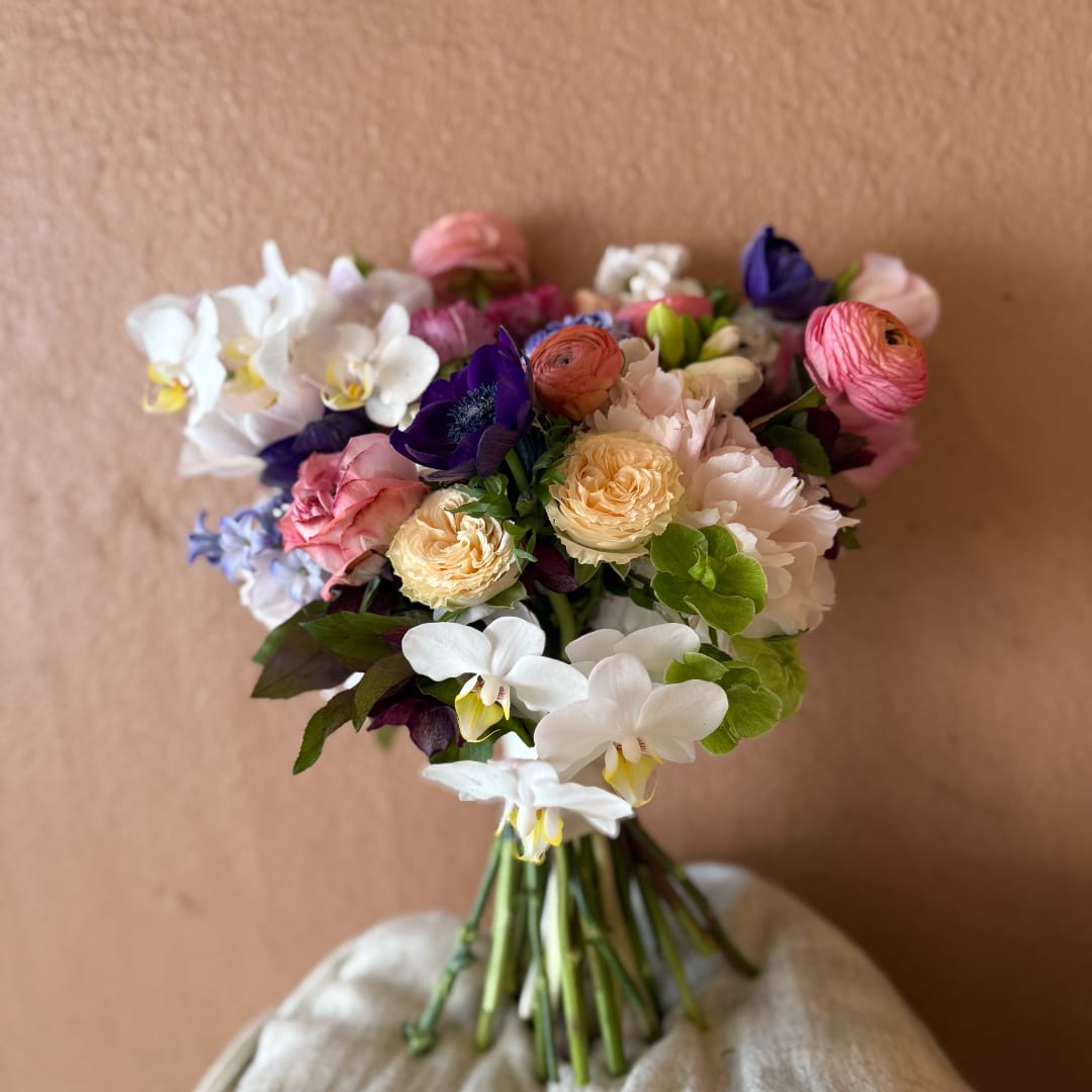 Wedding bouquet with white orchids, pink and cream roses, and purple blooms