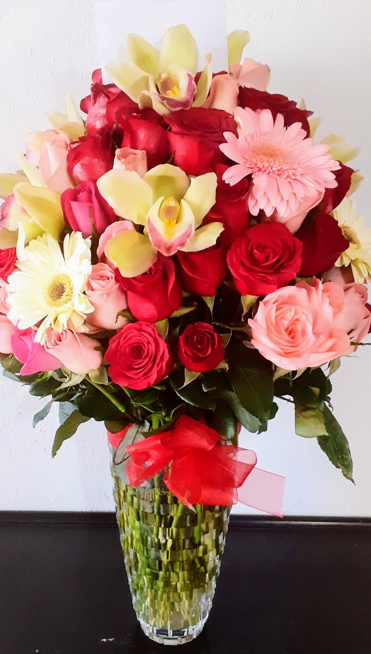 Royal Romance Orchid Garden - Luxury floral arrangement designed with premium red roses, pink roses, cymbidium orchids, gerbera daisies, and fresh seasonal blooms arranged in an elegant glass vase. Perfect for anniversaries, birthdays, romantic occasions, Valentine’s Day, luxury gifts, congratulations, and special celebrations. Same-day flower delivery available throughout San Antonio TX including Stone Oak, Alamo Heights, Medical Center, North Star, Cibolo, Schertz, and surrounding areas. Handcrafted floral arrangements made fresh daily using premium flowers for unforgettable moments.
