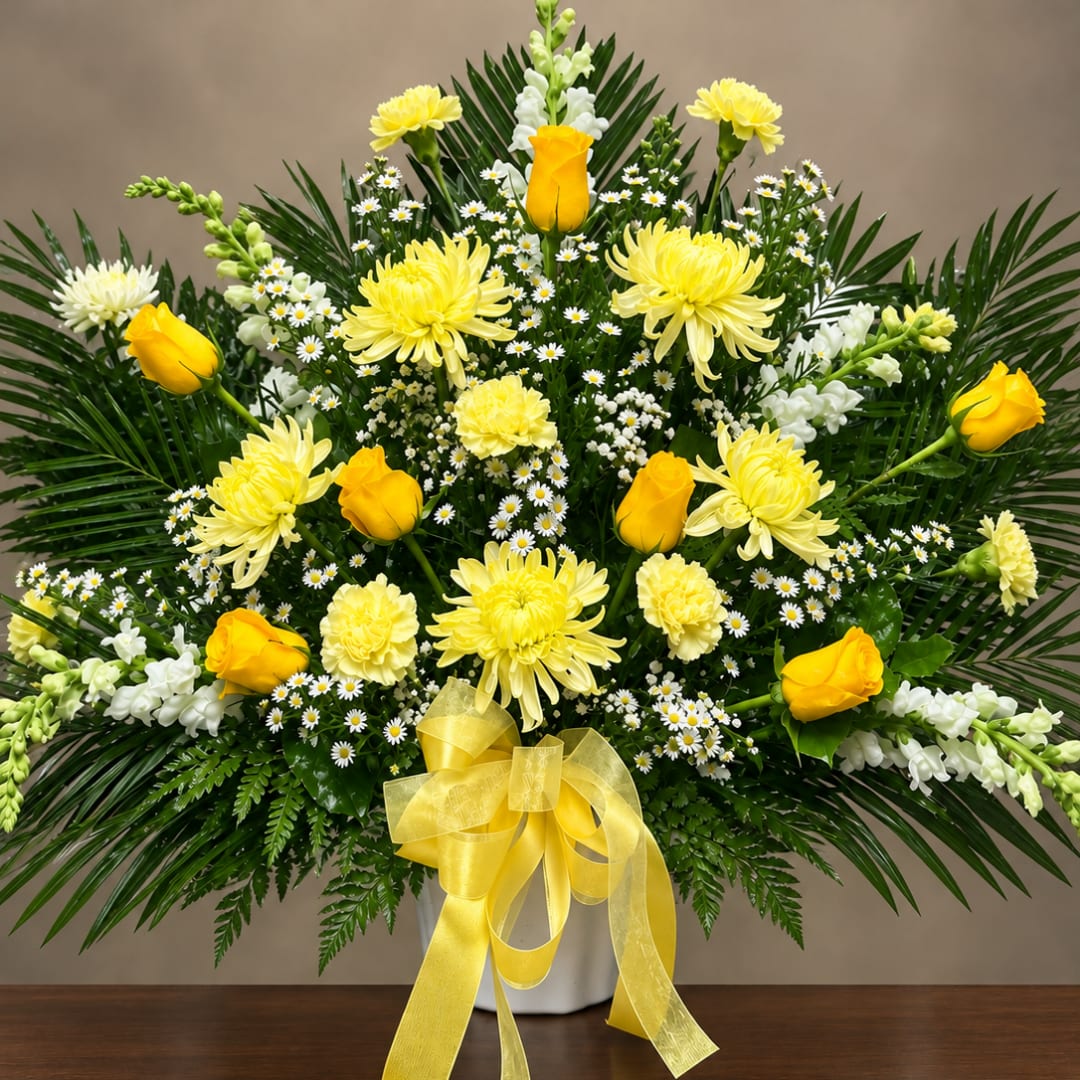 Yellow roses and chrysanthemums in a white vase with a yellow ribbon