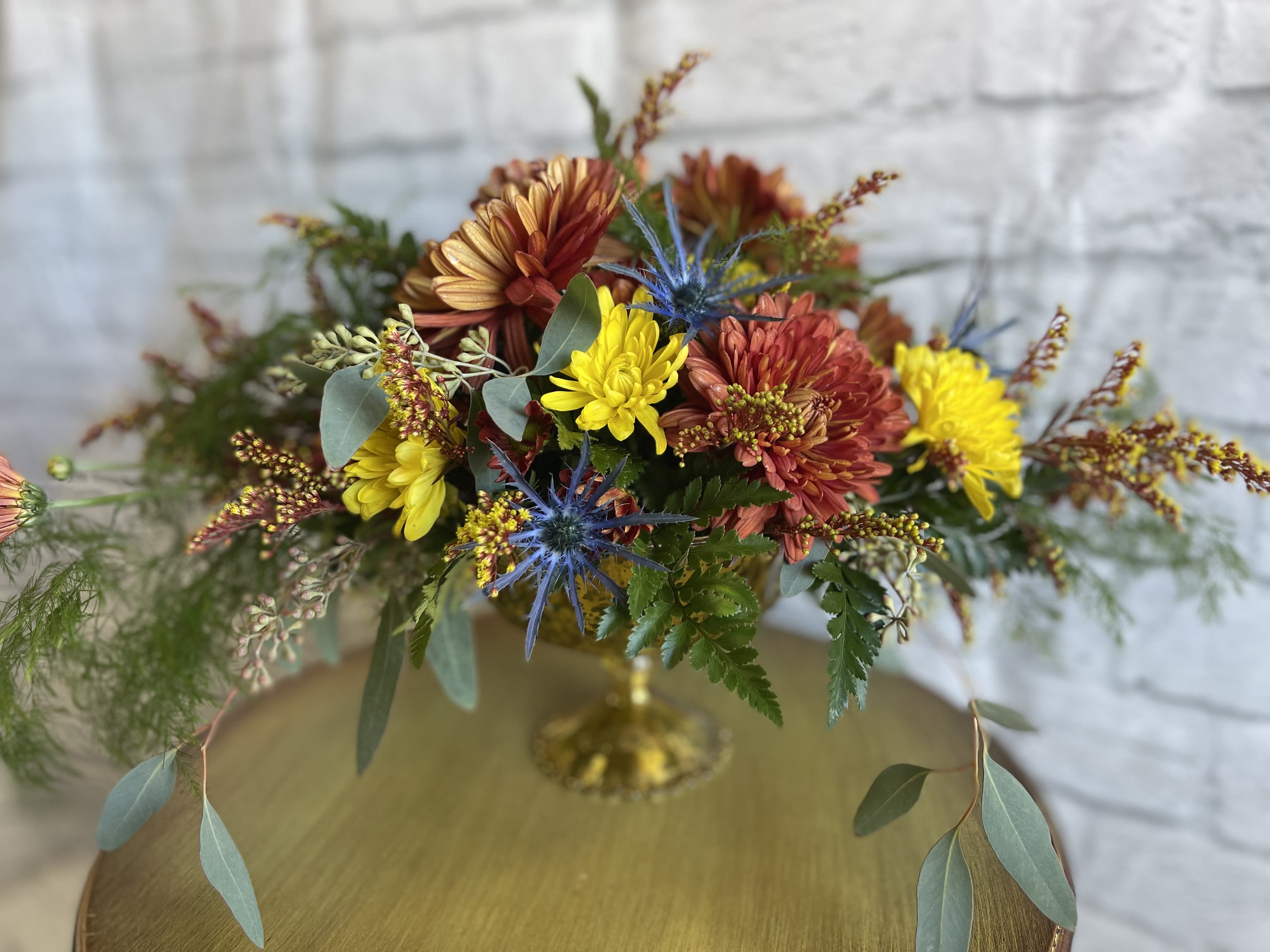 Autumn Glam - A  garden styled arrangement. Autumn toned flowers arranged in a  Mercury glass bowl creates a glamorous autumn centerpiece. (All designs are arranged as similar as possible. We promise to keep the same color, style, and overall theme with what Mother Nature generously blesses us with)