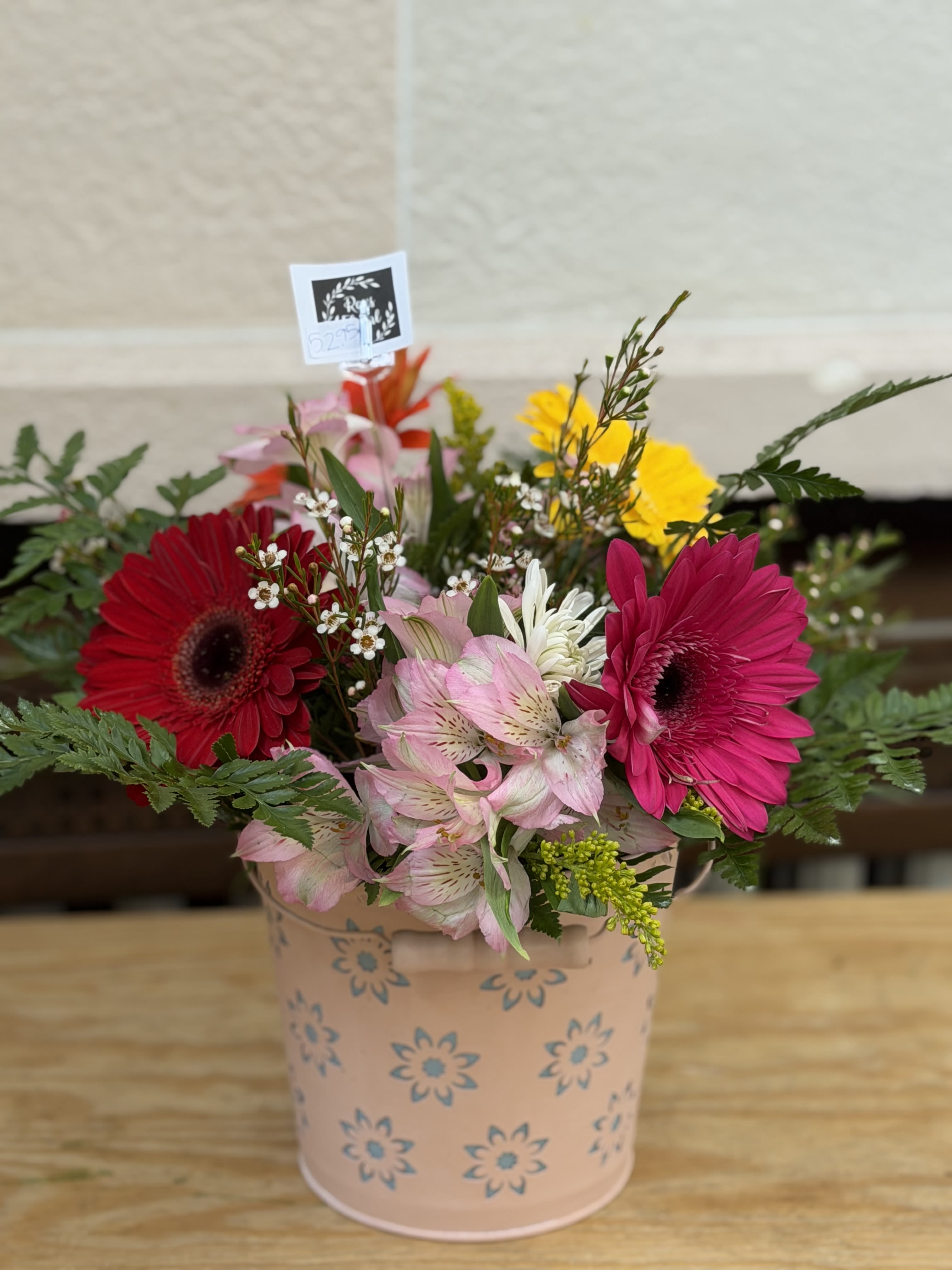 Mixed gerbera daisy bouquet in a pink floral tin