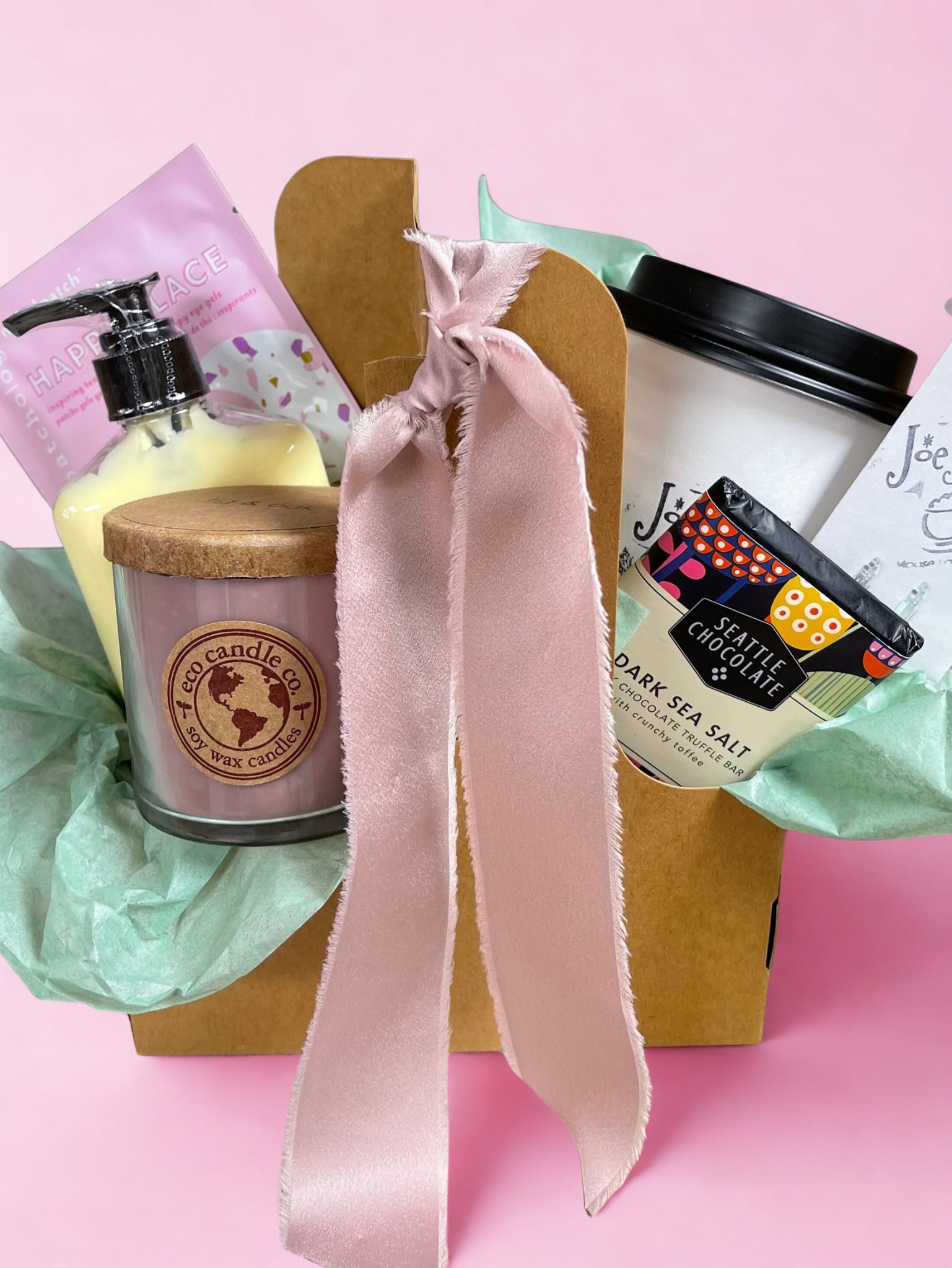 Gift basket with a candle, lotion, and chocolate bar tied with a pink ribbon