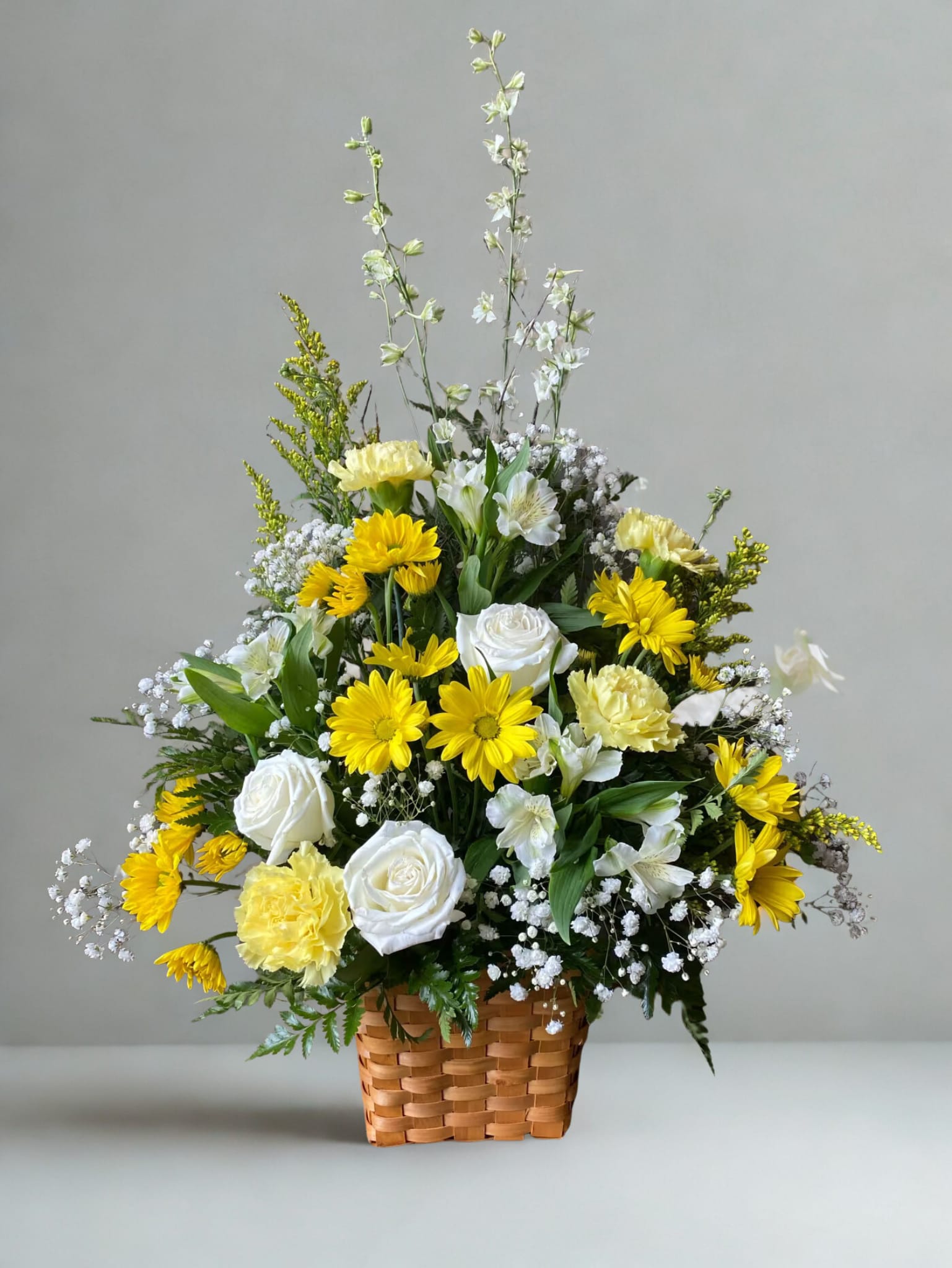 Guiding Light - Bright yellow and white florals fill a basket. A wonderful arrangement for any funeral. All flowers and colors may vary due to availability.