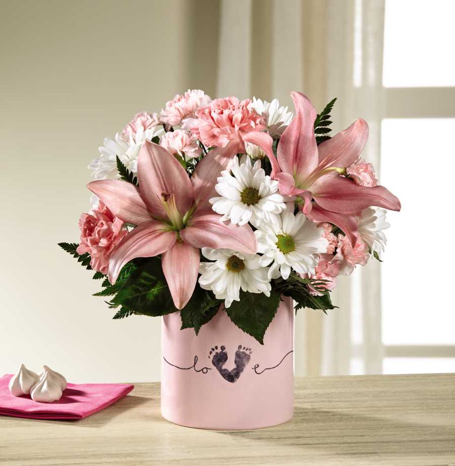 Pink lilies and white daisies in a pink vase with a baby footprint design