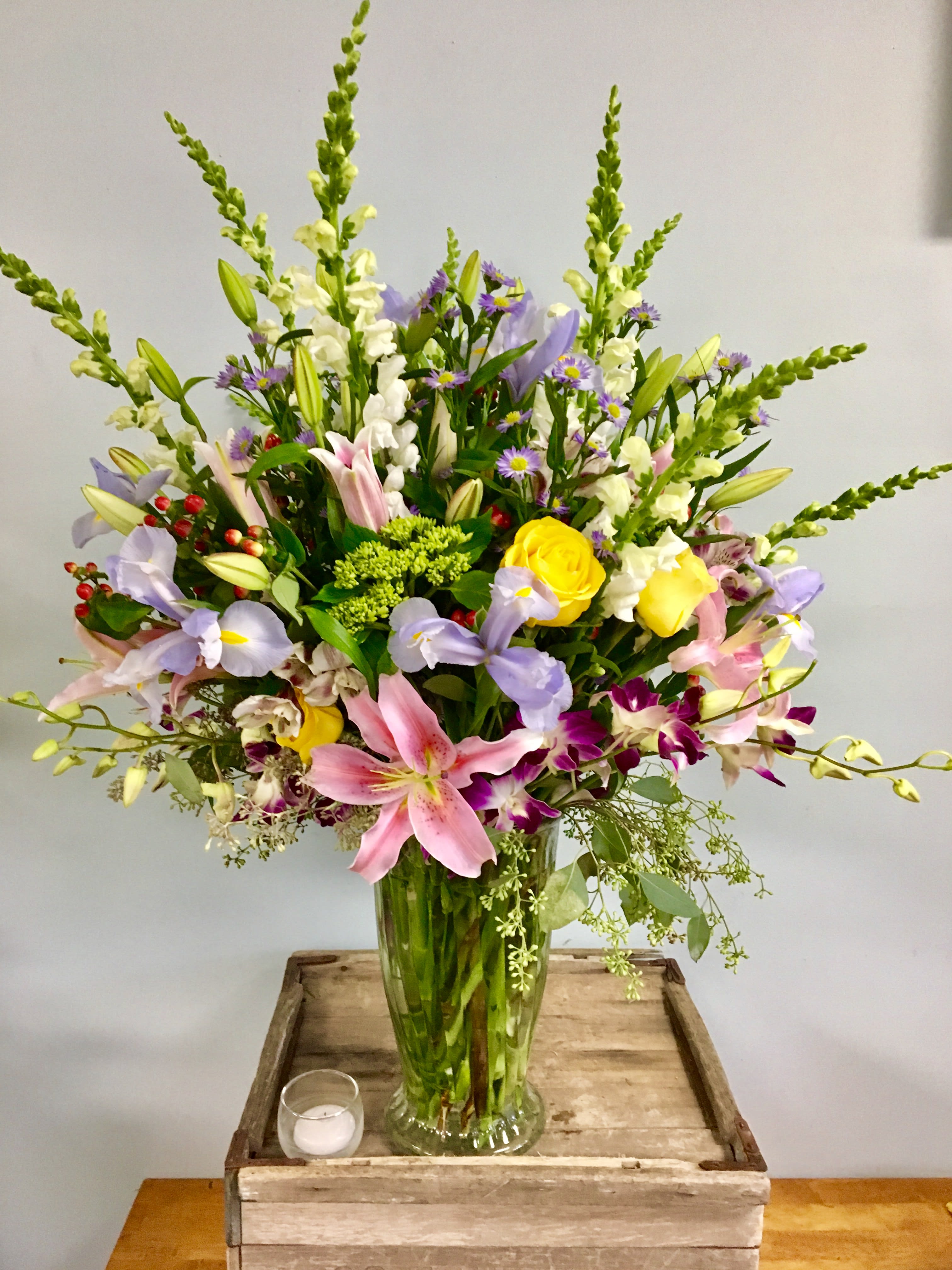 Mixed bouquet of lilies, roses, and orchids in a glass vase