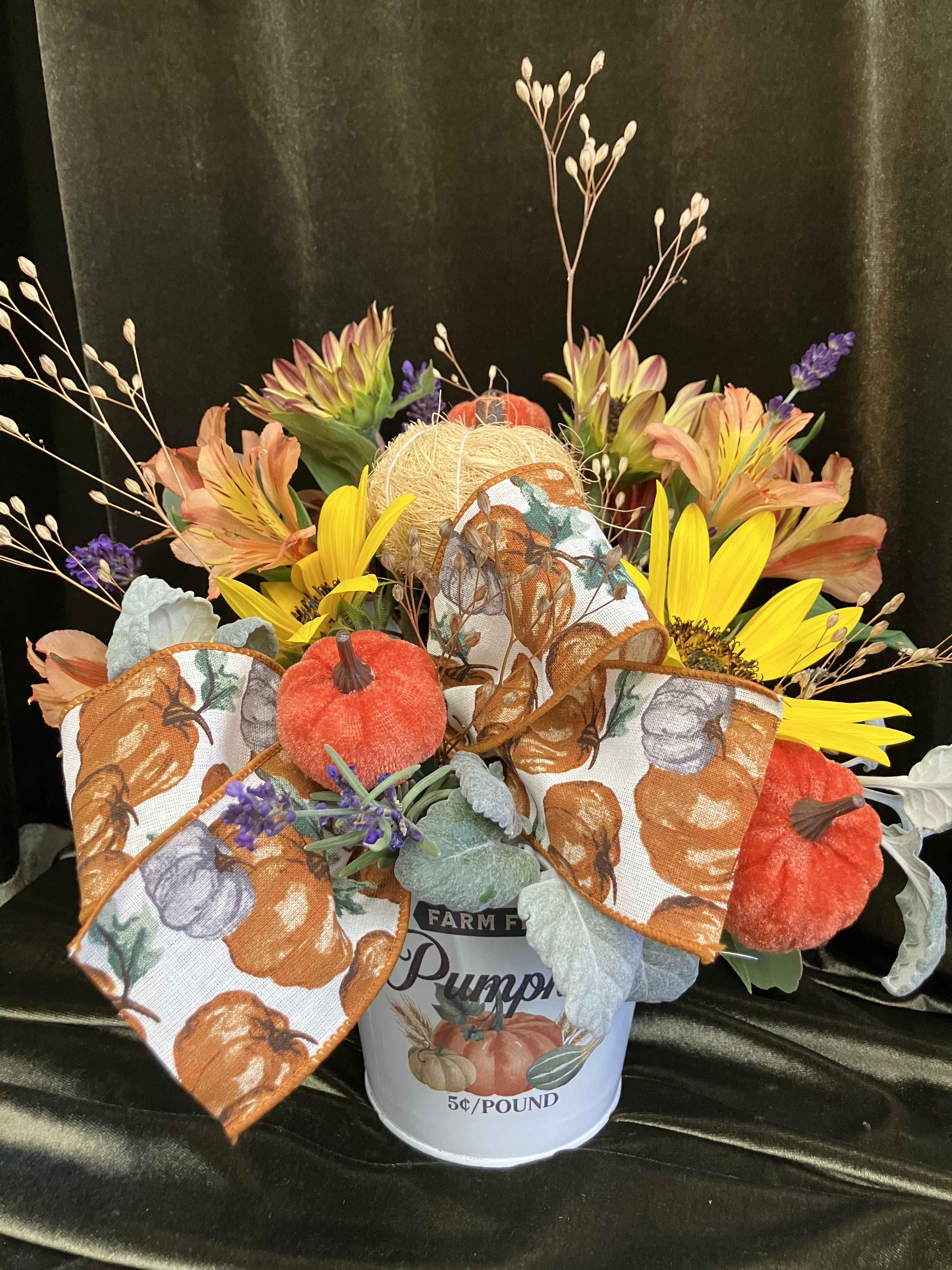 Fall bouquet with sunflowers, orange blooms, and pumpkin ribbon in a white bucket