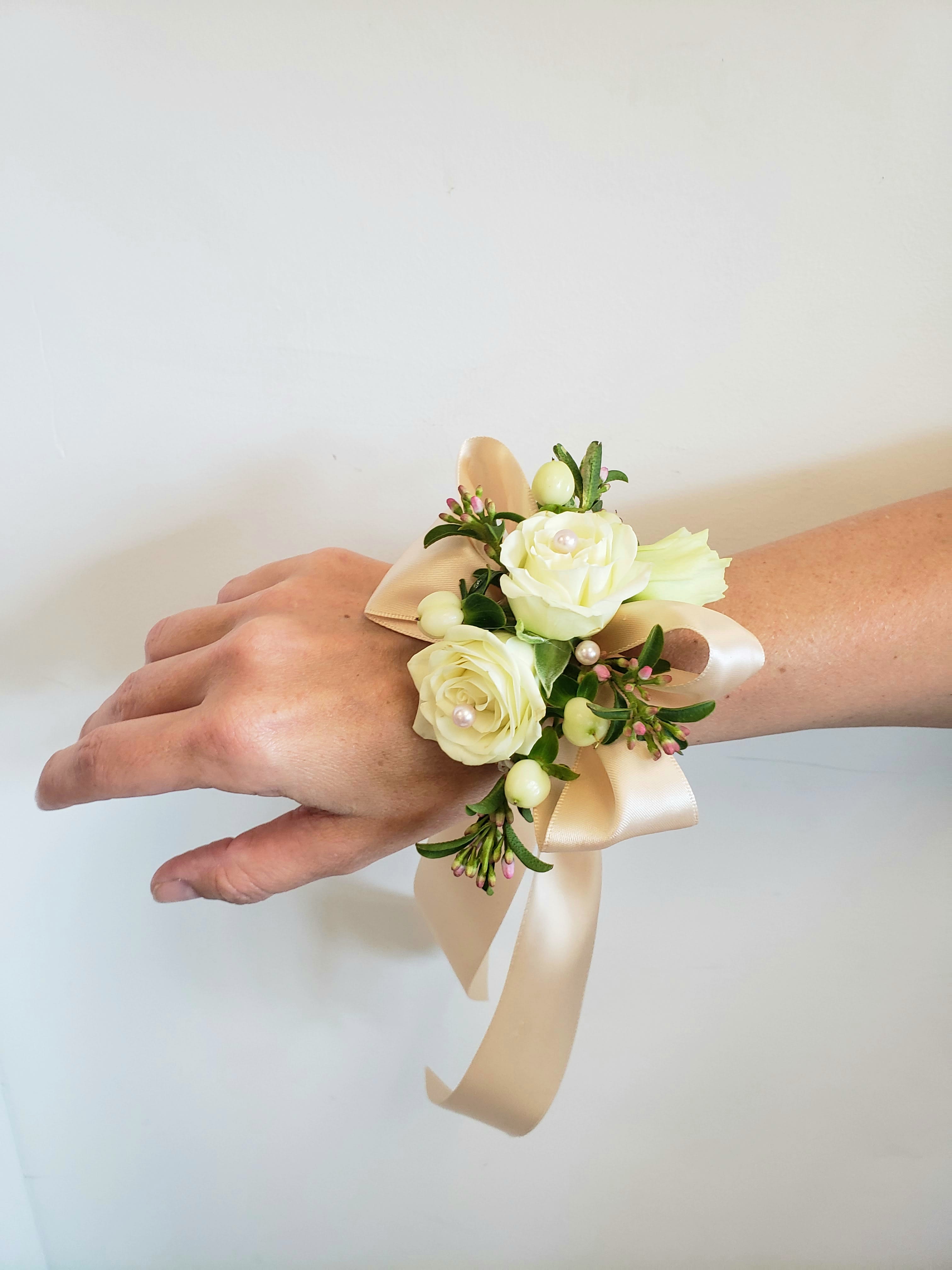 Cream rose wrist corsage with ribbon on a person's wrist