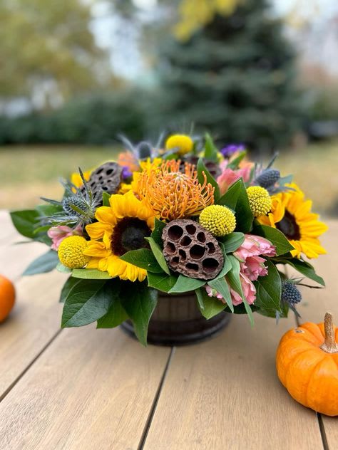 Autumn bouquet with sunflowers and orange blooms in a low container