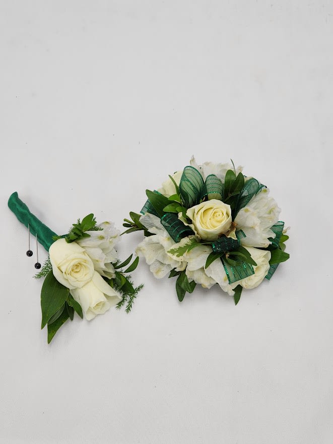 Two white rose boutonnieres with green ribbon accents