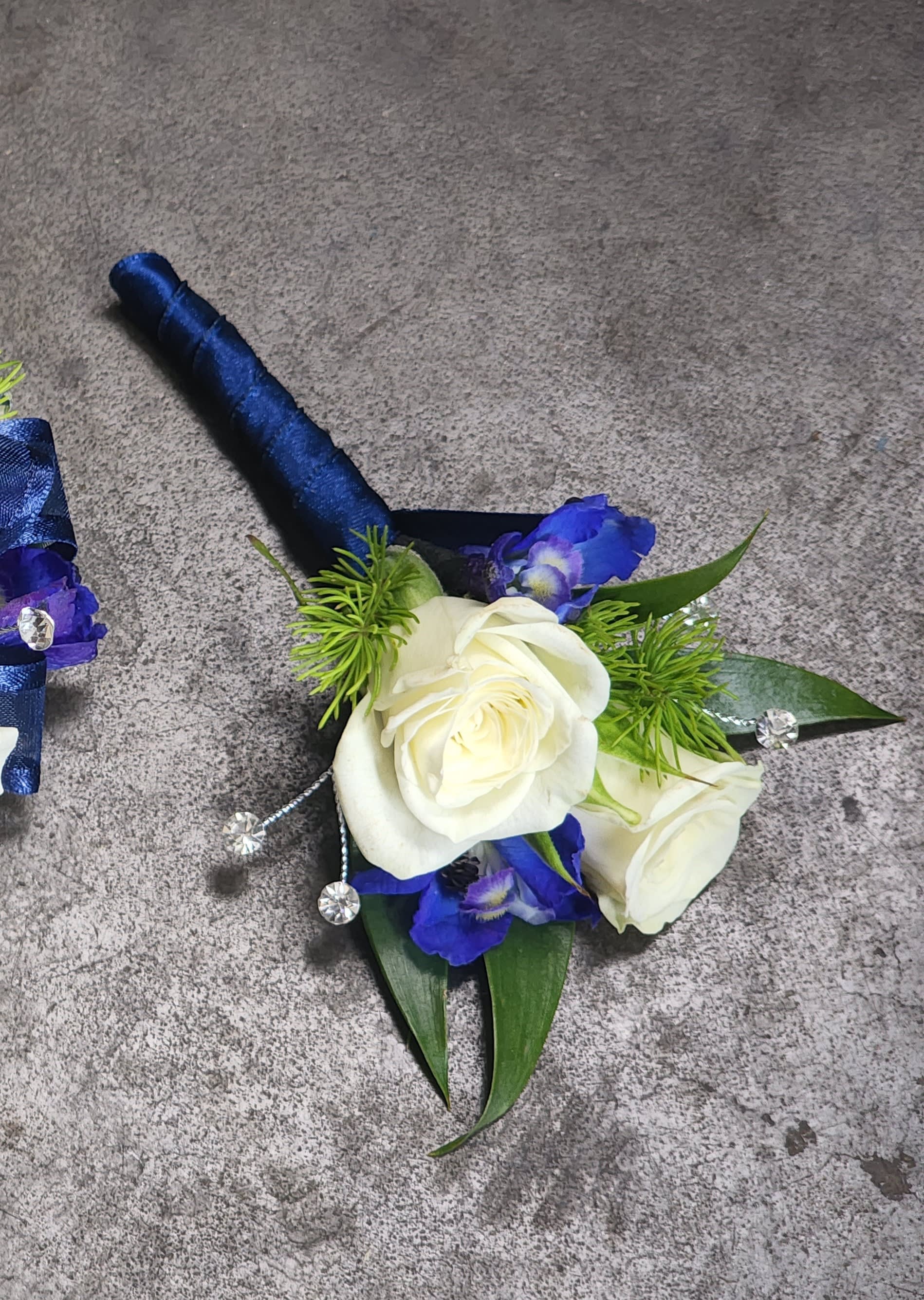 Blue Elegance Boutonniere - A boutonniere of white spray roses, dark blue belladonna, dark blue ribbon &amp; clear rhinestones.  Depending on availability of ribbon, may change slightly.