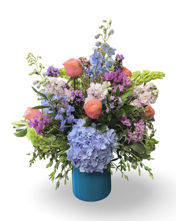 Mixed bouquet of blue, purple, pink, and white flowers in a blue vase