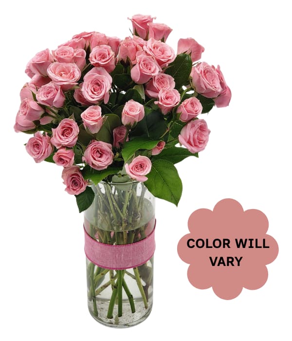 Pink roses arranged in a clear glass vase with a pink ribbon