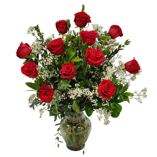 Red roses arranged in a clear glass vase with white filler flowers