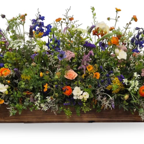 Mixed bouquet of colorful flowers arranged in a low wooden container