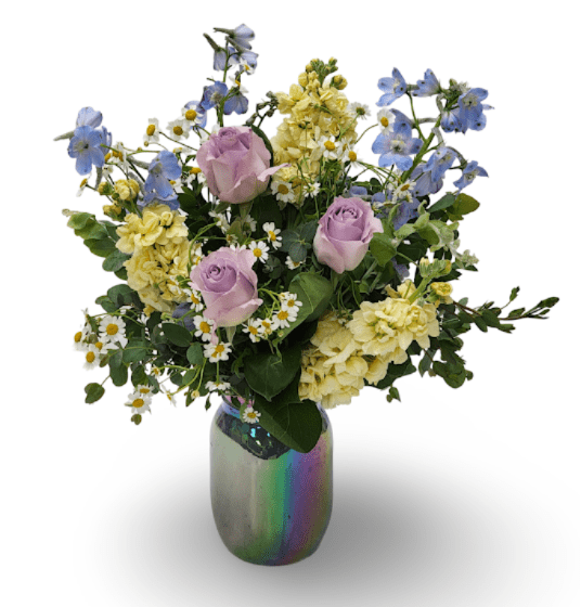 Sweet Pastels - Soft and soothing like a summer breeze, Sky Bloom brings together calming blue Bella Donna, elegant lavender roses, sunny yellow stock, and cheerful chamomile. Arranged in a glowy iridescent blue mason jar, this bouquet feels like a little jar of light and love — perfect for brightening someone’s day.  Approximately 18" x 14" x 12"