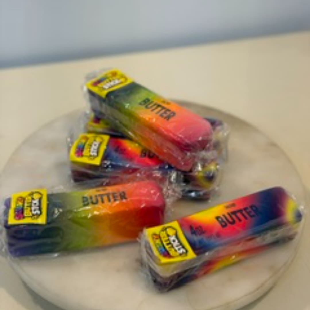 Four packaged rainbow butter sticks on a round tray
