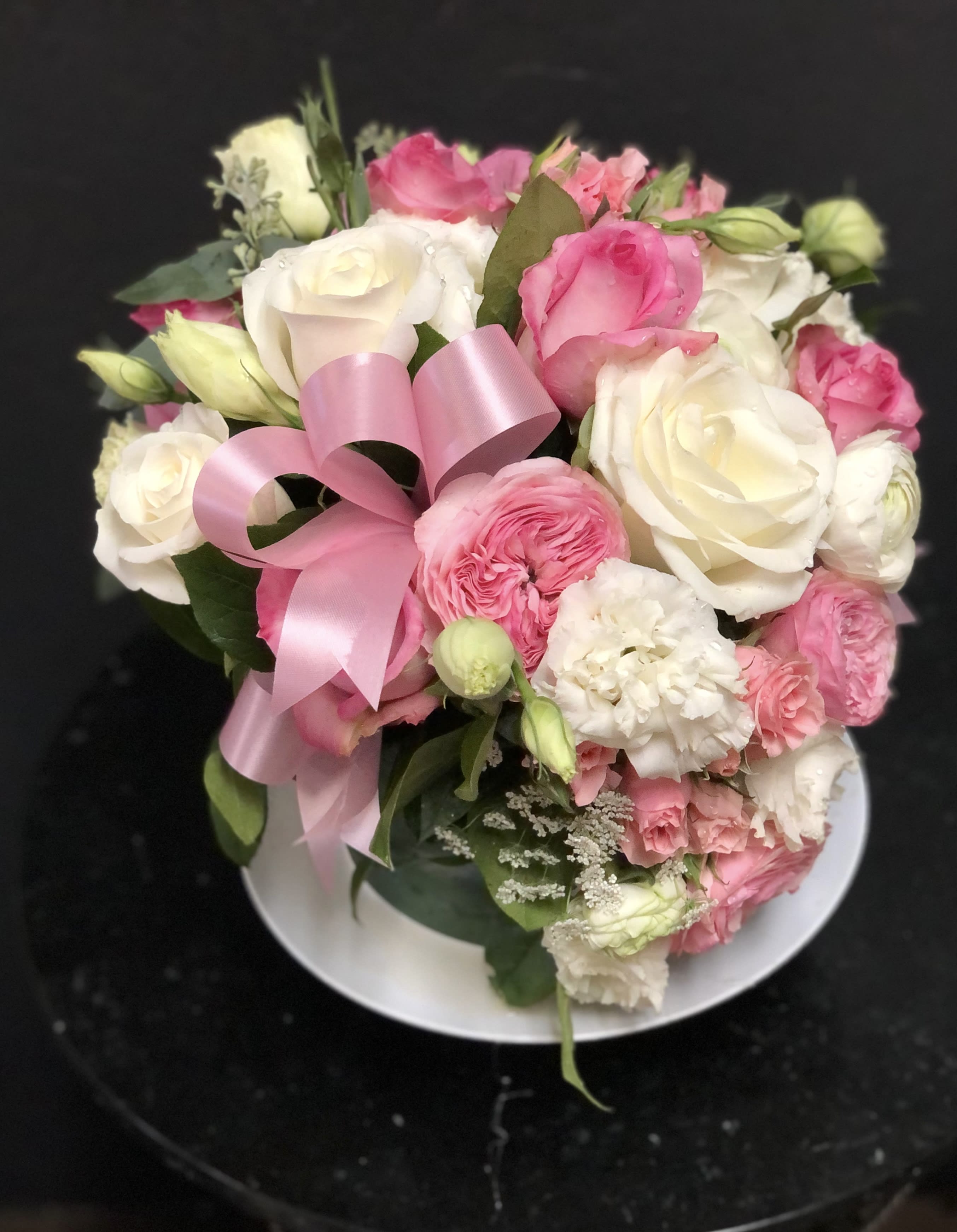 Pink and white rose bouquet with a pink ribbon on a plate