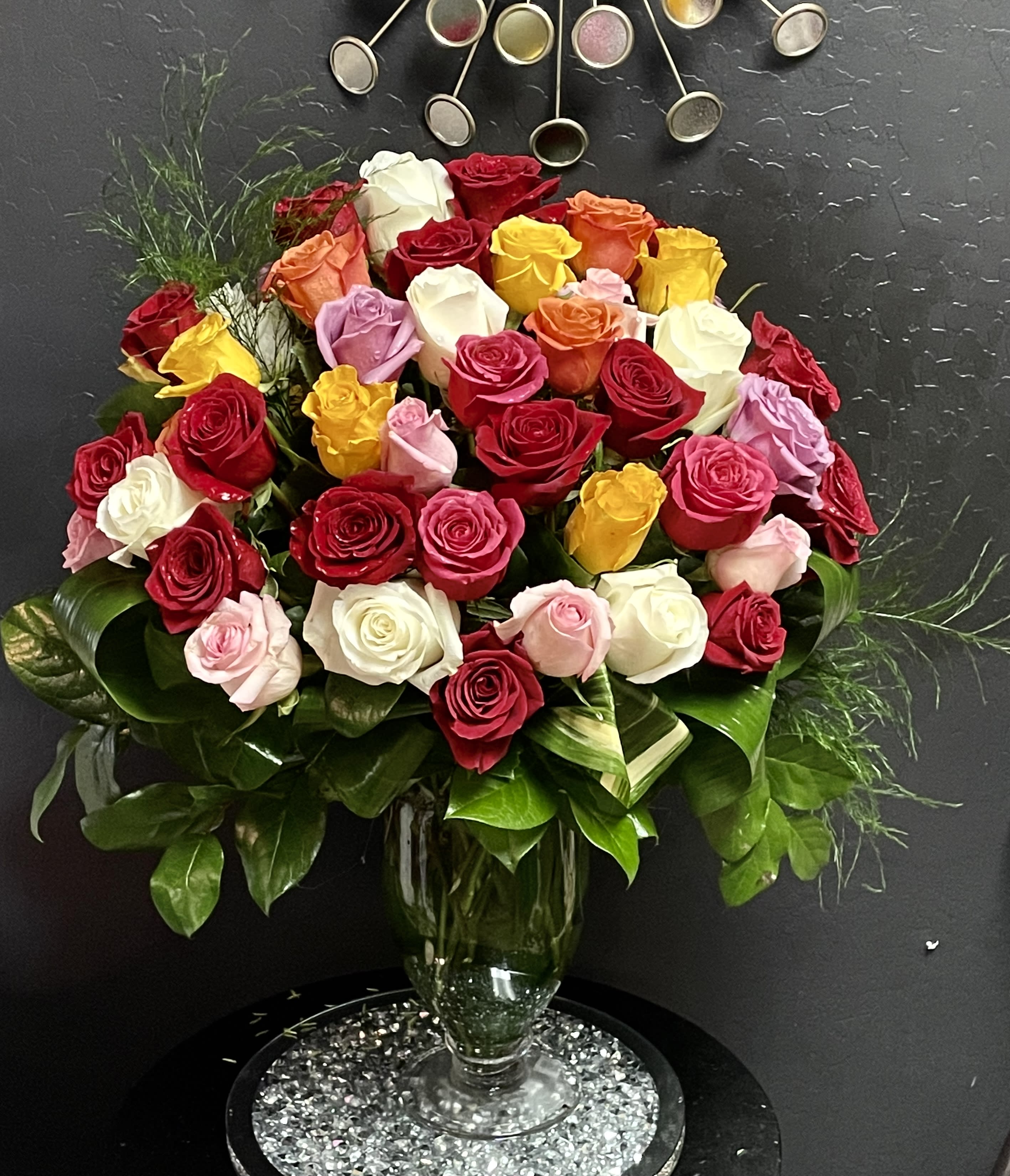 Mixed roses in a glass vase with glossy greenery