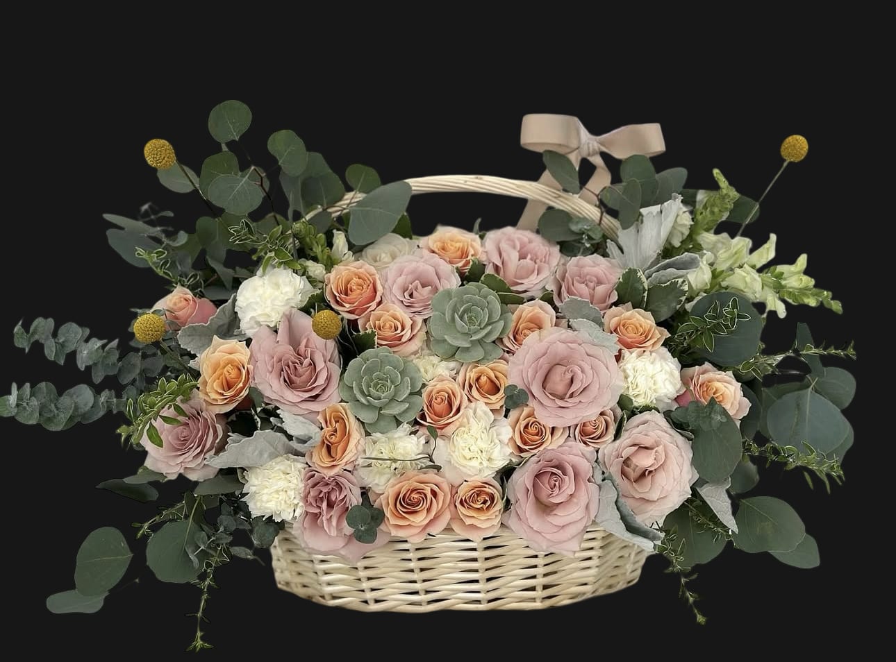 Ethereal Garden Basket - A refined basket arrangement featuring muted blush and peach roses, creamy carnations, fresh eucalyptus, golden billy balls, and elegant succulents. Finished with a satin bow, this design radiates timeless charm and organic elegance—perfect for sympathy, thank yous, or sophisticated home décor.
