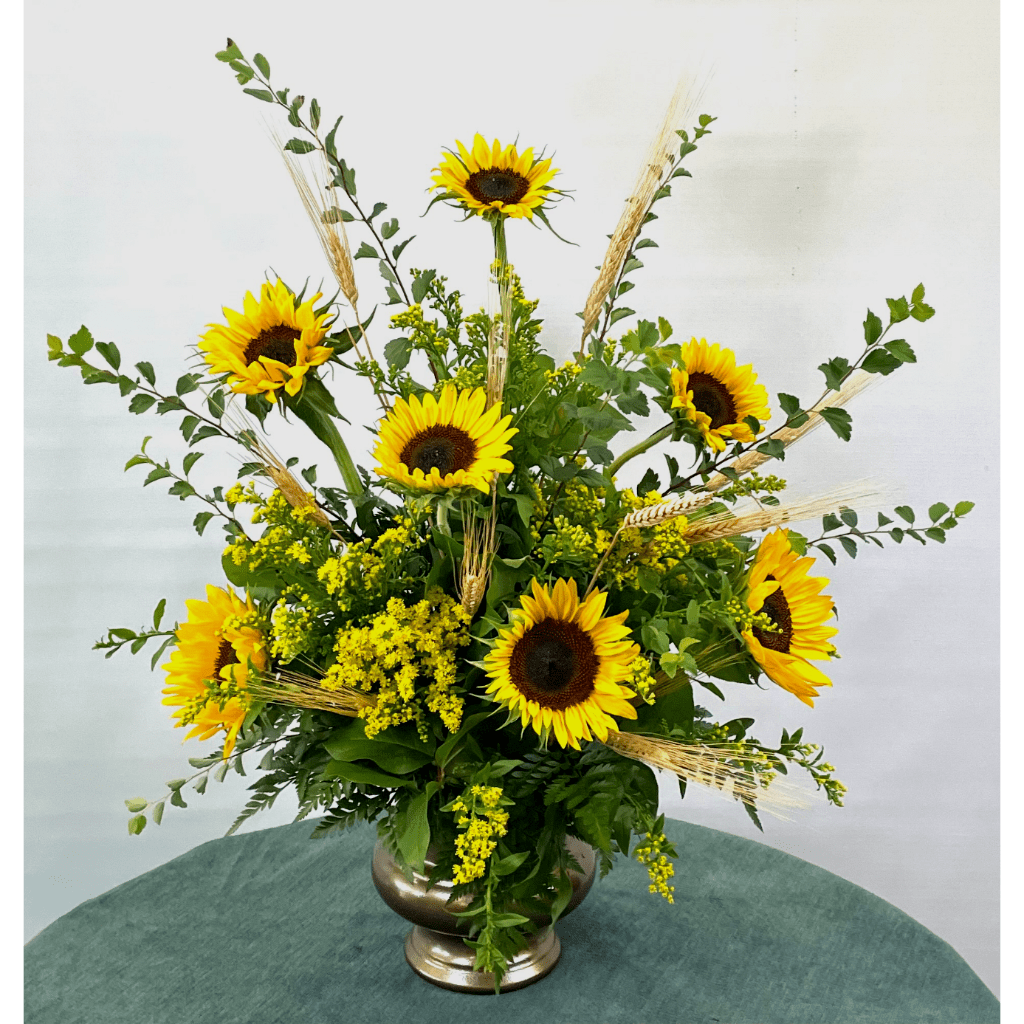 Sunflower arrangement in a silver vase with wheat accents