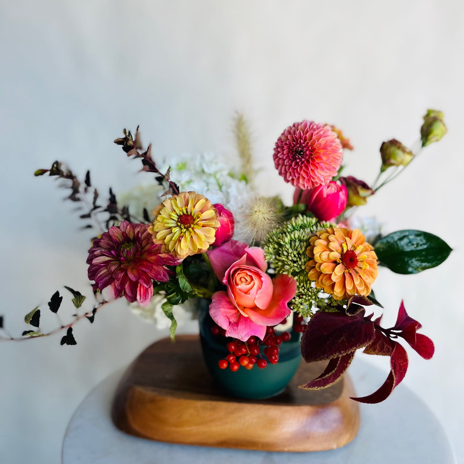 Mixed bouquet of pink, orange, and yellow flowers in a teal vase