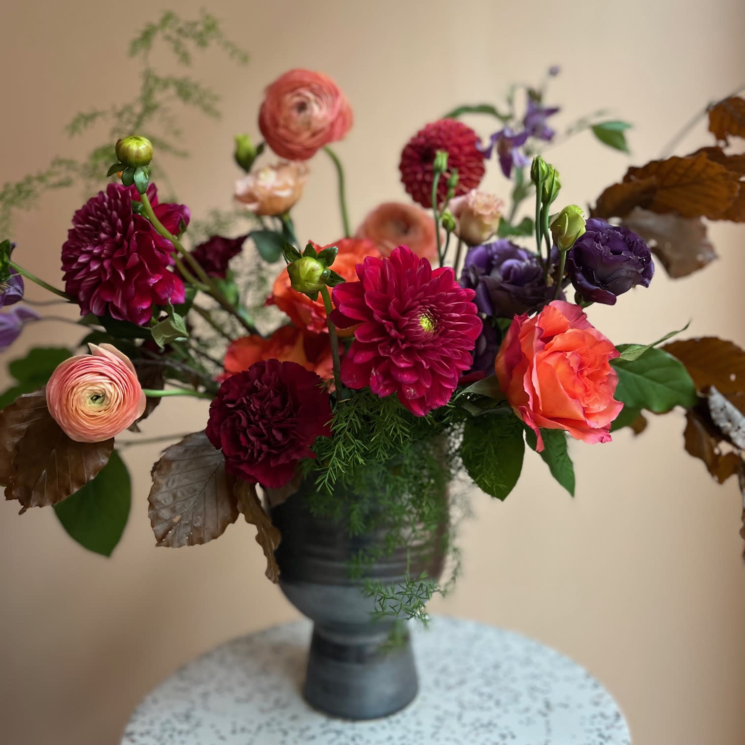 Mixed bouquet of bright flowers in a dark vase