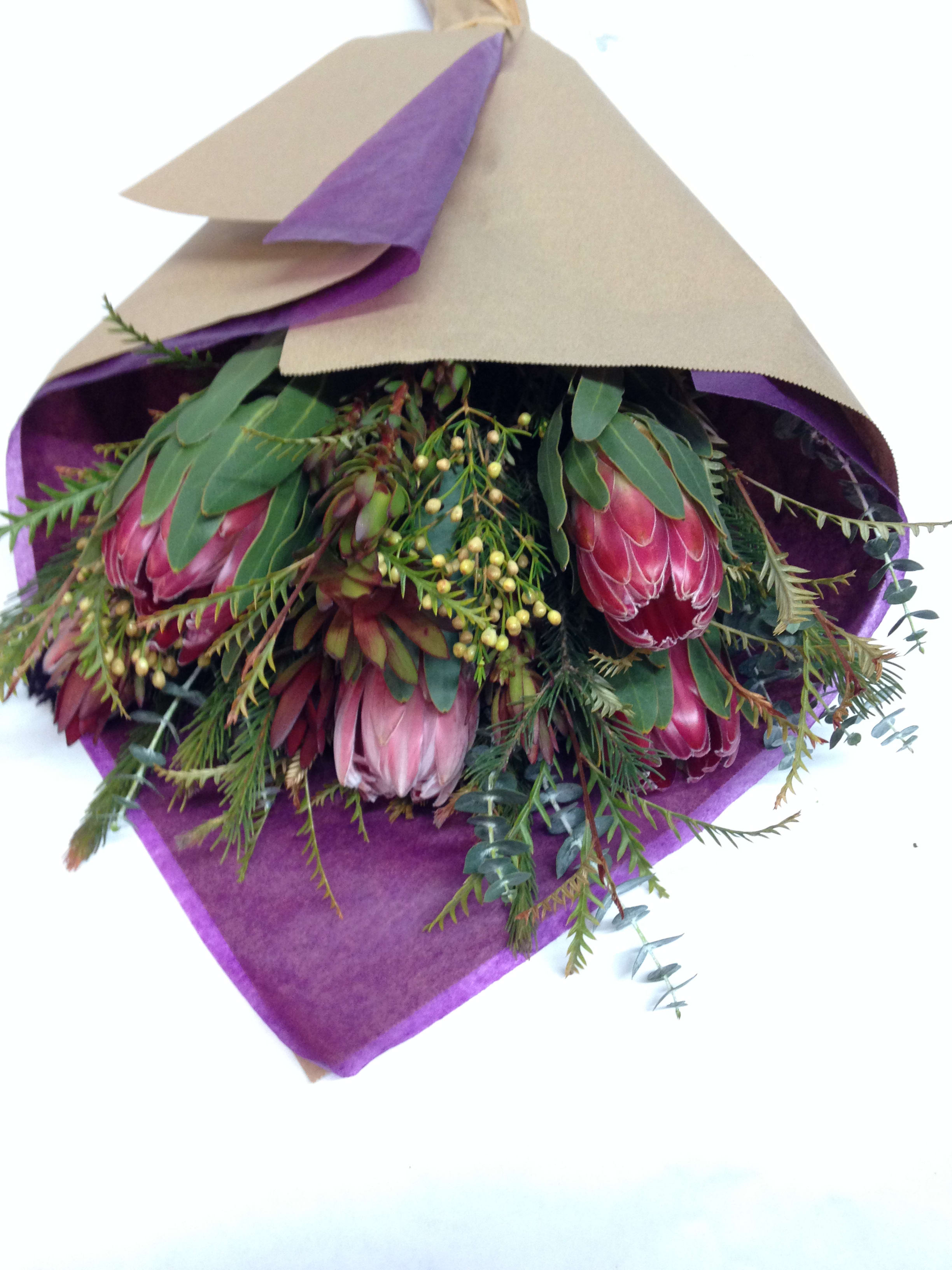 Bouquet of pink protea wrapped in purple and tan paper
