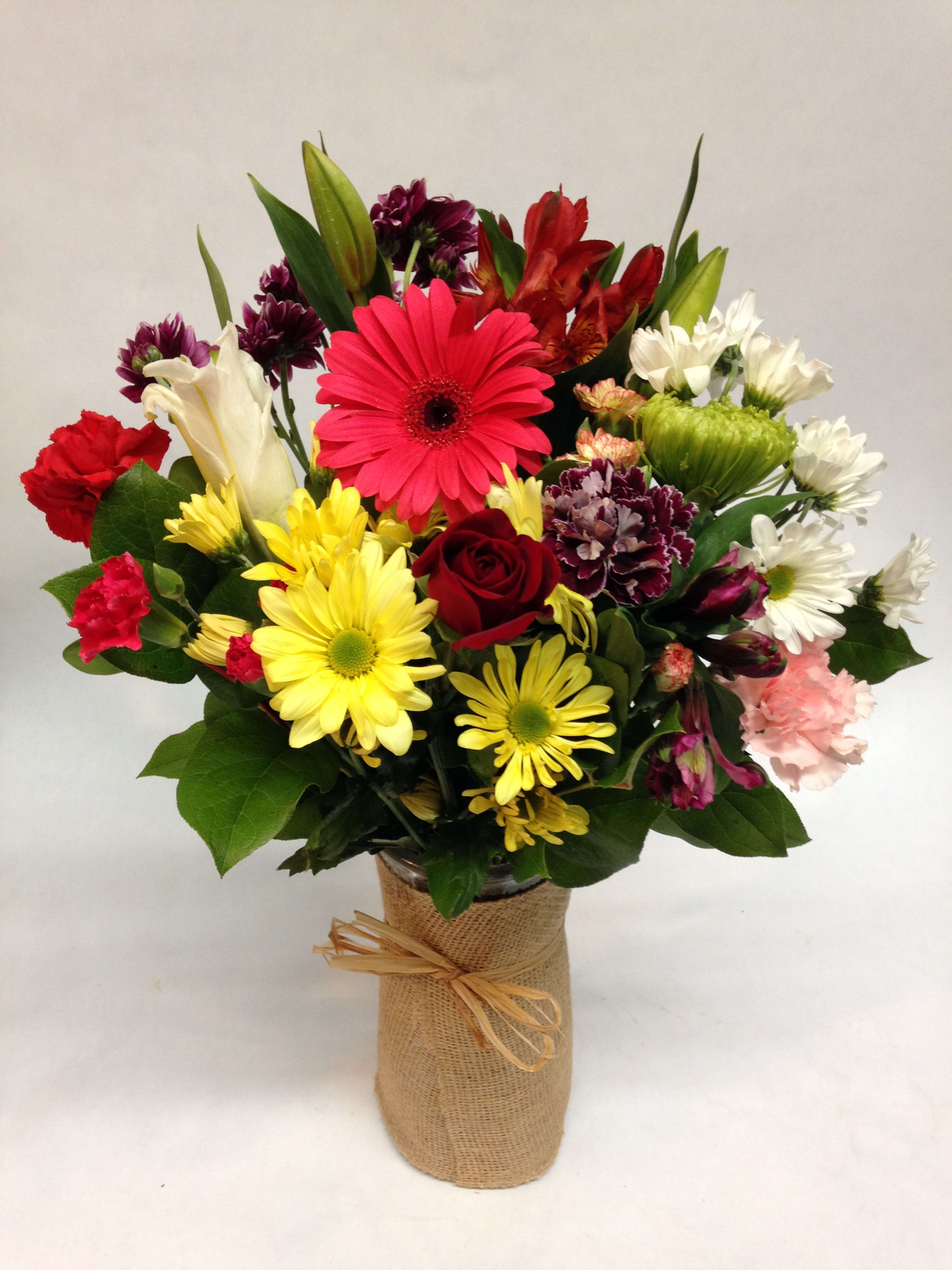 Mixed bouquet of colorful flowers in a burlap-wrapped vase