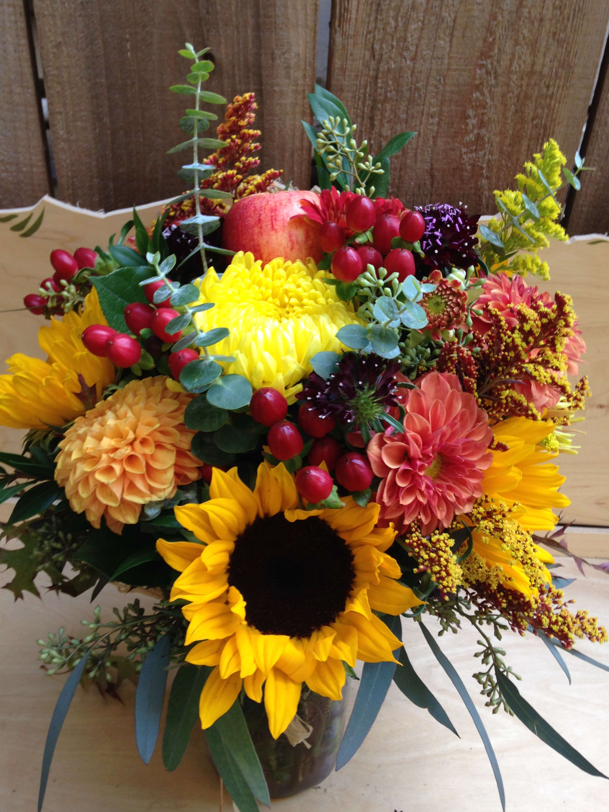 Autumnal Wild Flower Jar - A sweet mix of sunflowers, dahlias, solidago, and other harvest greens. Put together in a mason jar for a rustic look. (Some flowers may be substituted due to seasonal availability) Featured Arrangement: $88.75