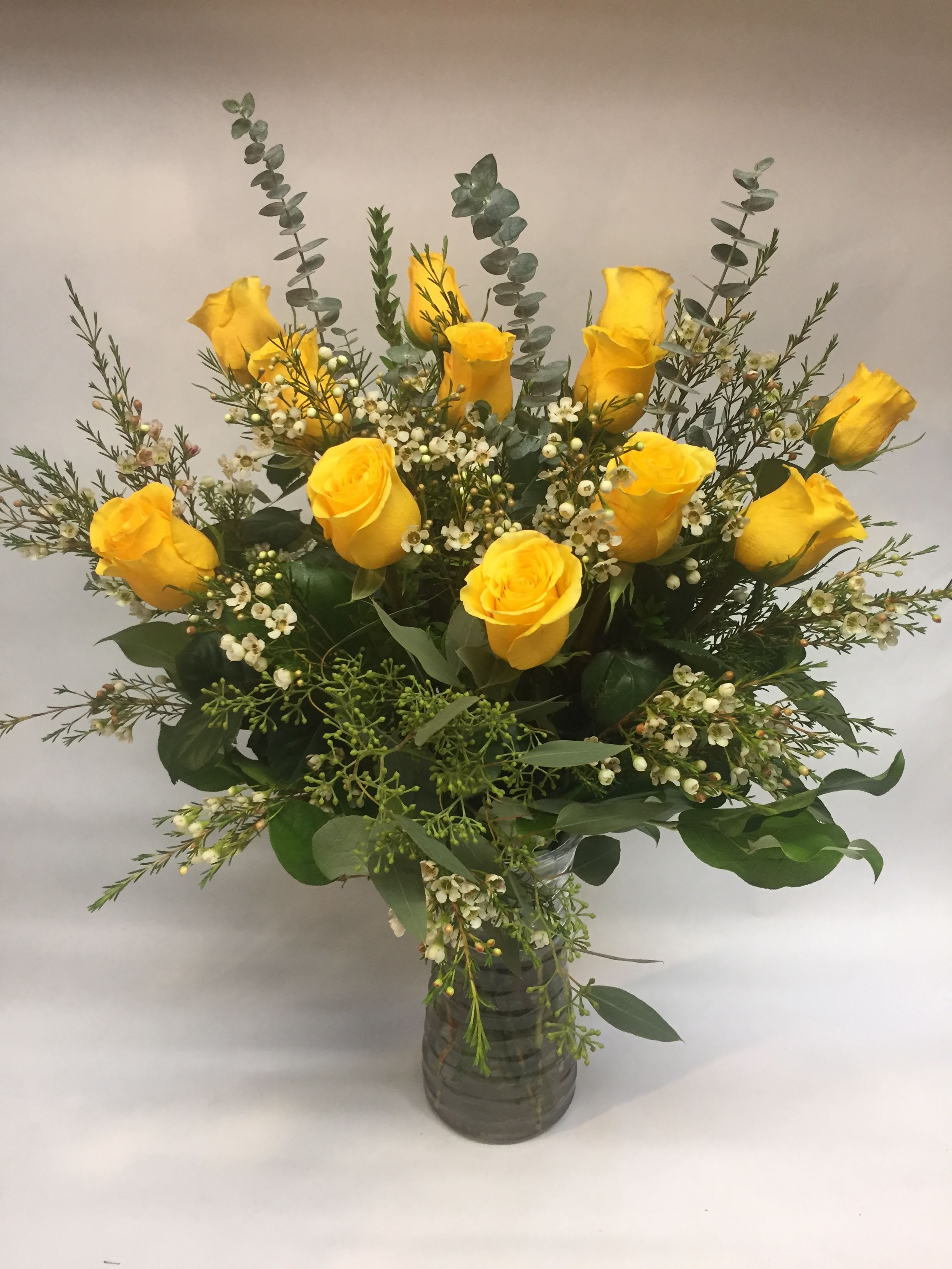 Yellow roses arranged in a clear glass vase with white filler flowers