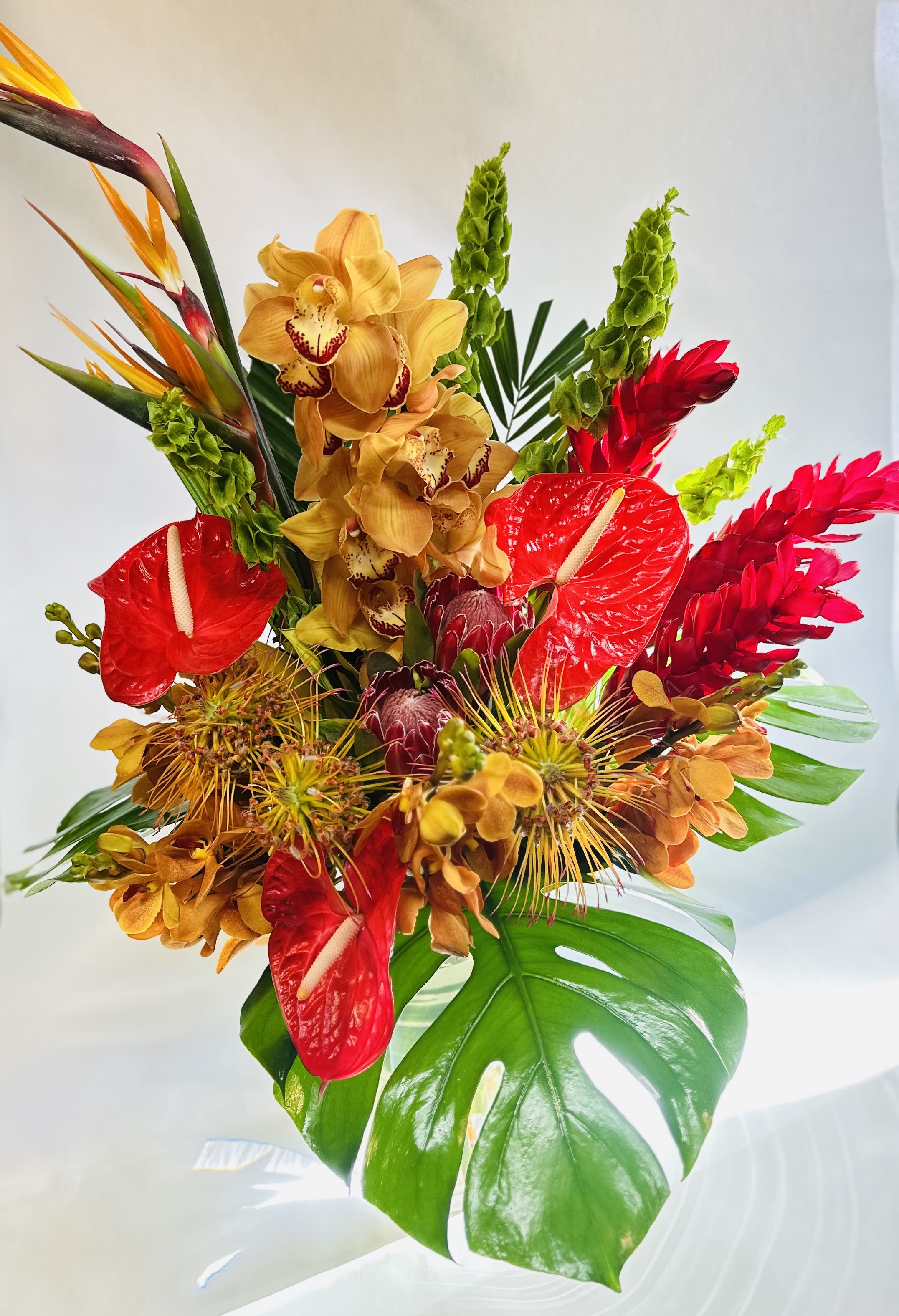 Tropical bouquet with red anthuriums, yellow orchids, and bird-of-paradise