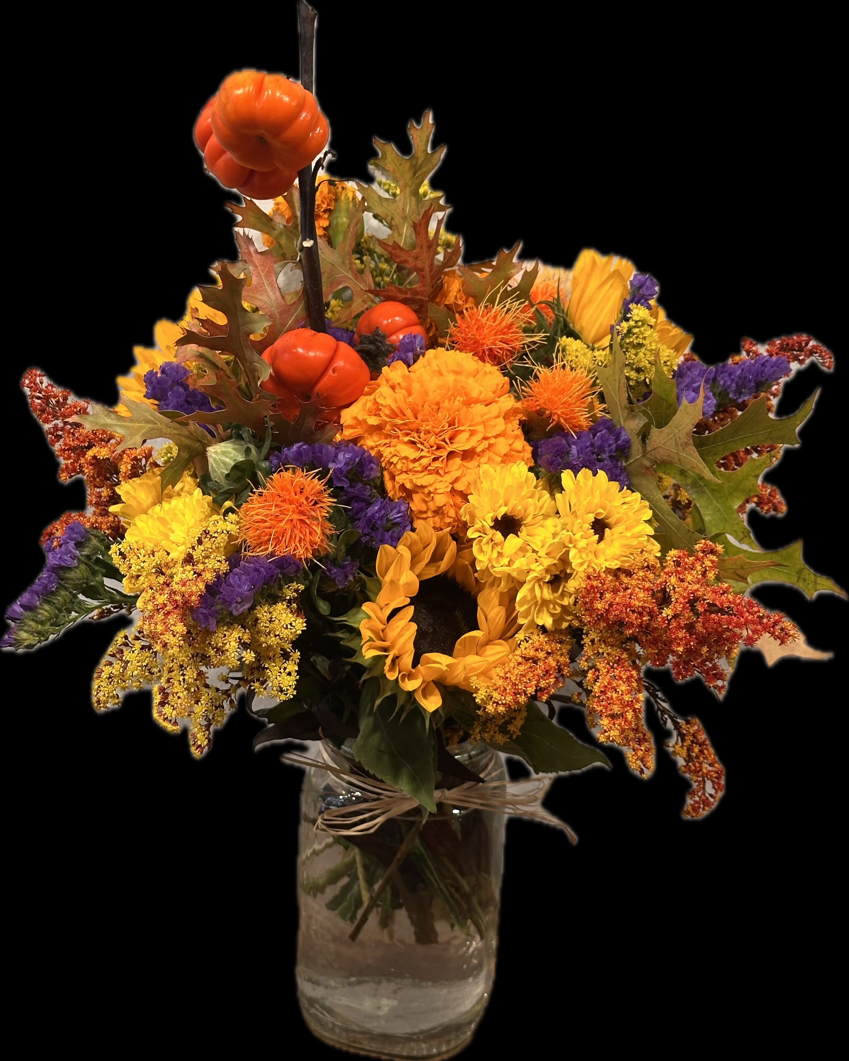 Autumn bouquet of sunflowers, chrysanthemums, and orange pumpkins in a glass vase