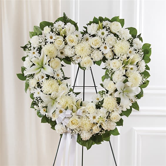 Always Remembe Floral Heart Tribute- White - The enduring love you feel for them will keep them always remembered. This sentiment is best captured with our standing, open heart-shaped arrangement in all white. Handcrafted by our caring florists with an assortment of flawless white blooms, it is a magnificent tribute fitting for the funeral services. •Open, heart-shaped arrangement of all white roses, hybrid lilies, football mums, carnations and daisy poms; accented with baby’s breath and soft, lush greenery •Arrangement is designed on an easel and accented with satin ribbon •Measures approximately 26"H x 28"W without easel •Appropriate for the funeral home •Our florists use only the freshest flowers available, so colors and varieties may vary