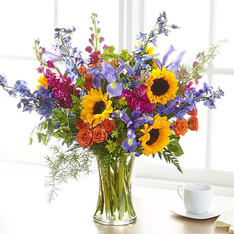 Rays of Life Bouquet - Show your loved ones how much you care with a bouquet full of bright, vibrant summer blooms. This bold bouquet is designed by a local florist, and is best fit for a home or residence. Bloom Details Sunflower Spray Rose Iris Delphinium