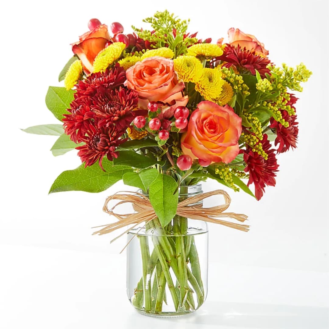 Bouquet of orange roses and red chrysanthemums in a clear glass vase