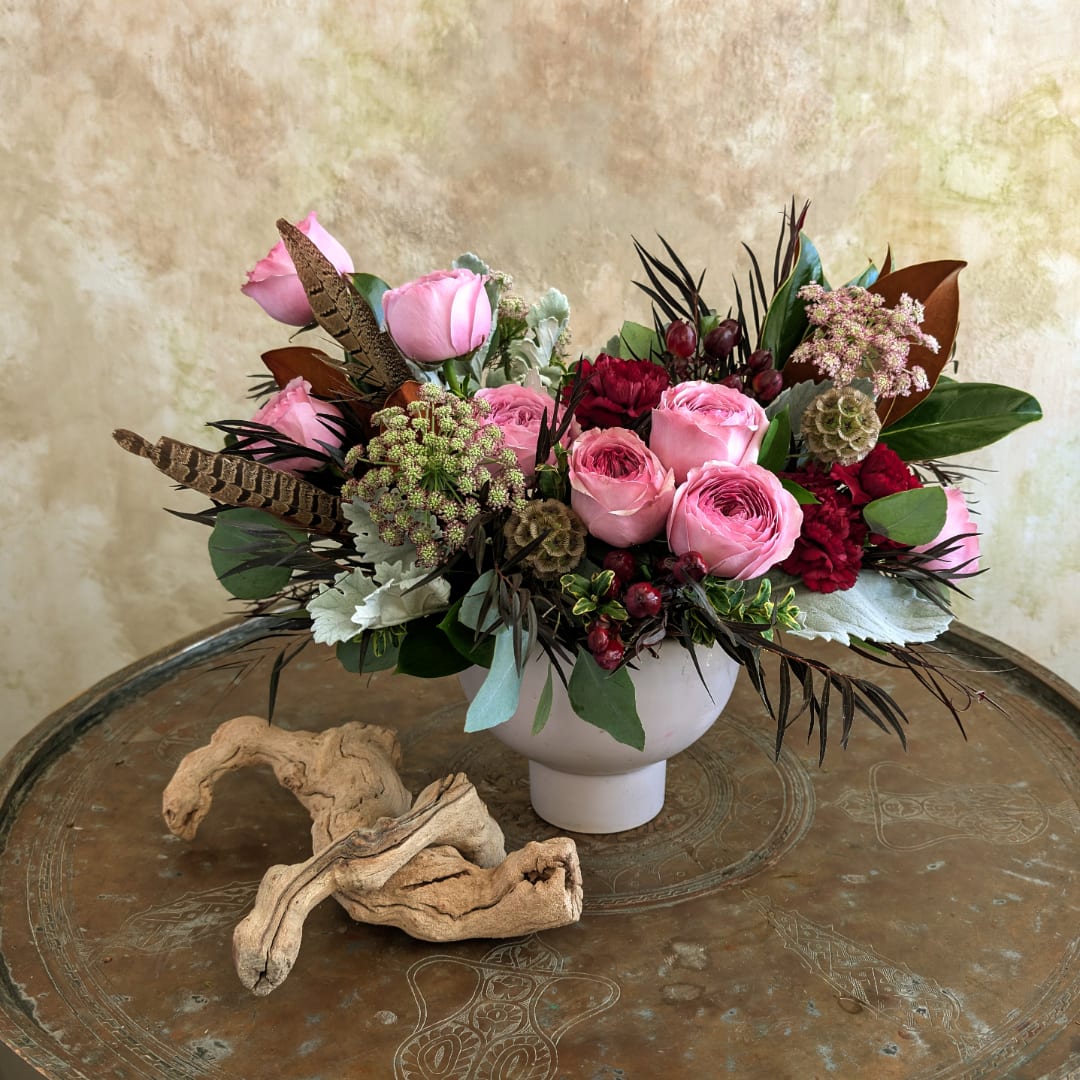 Pink rose arrangement in a white vase with mixed foliage and berries