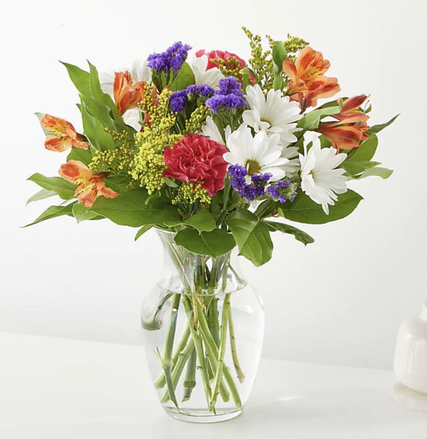 Mixed bouquet of daisies, carnations, and alstroemeria in a clear glass vase