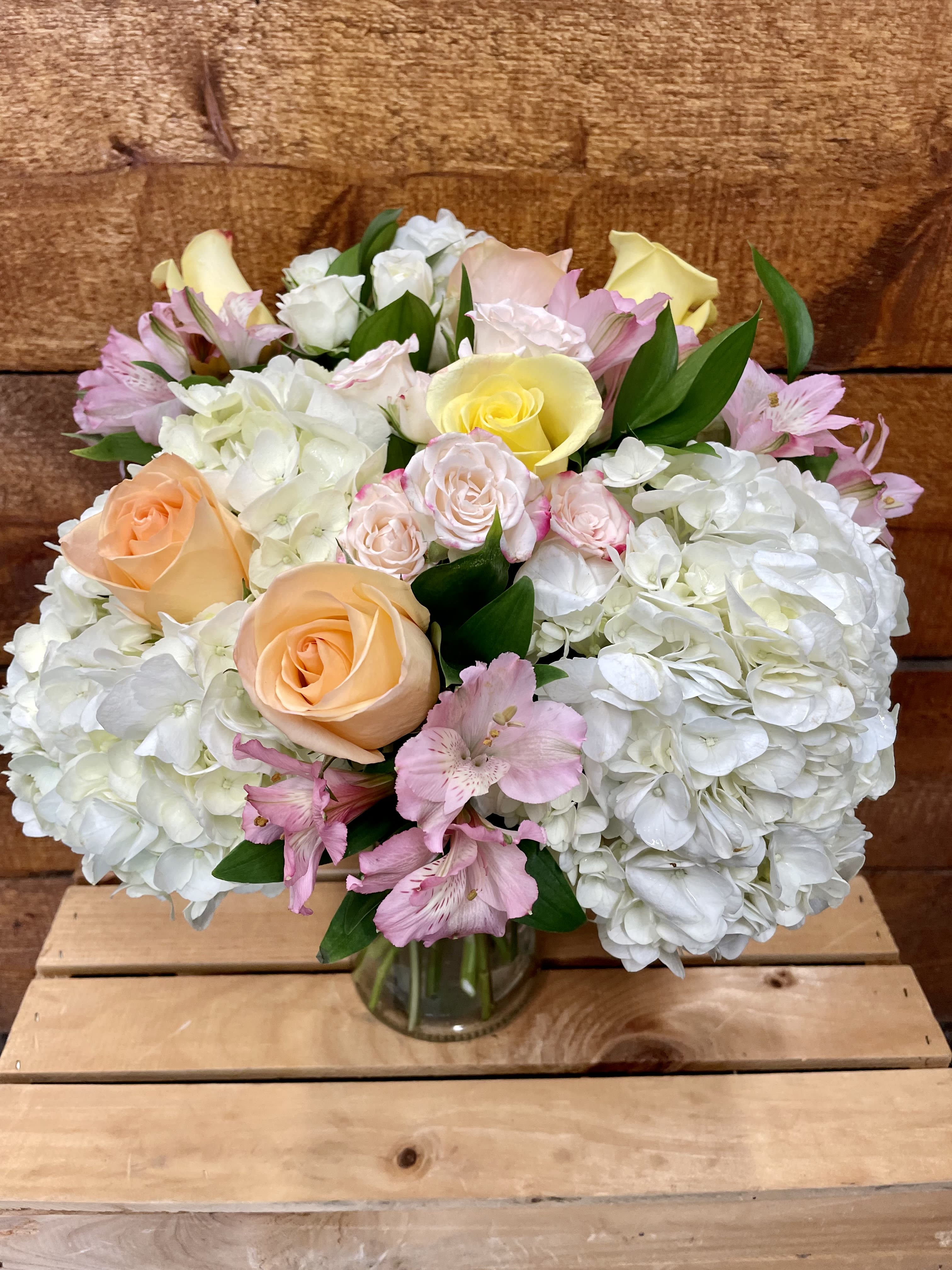 Bouquet of pastel roses, hydrangeas, and pink alstroemeria in a glass vase