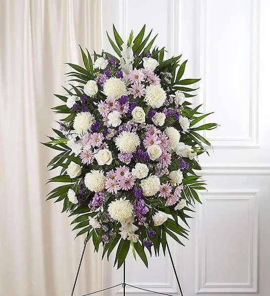 Standing funeral spray with white, pink, and purple flowers on an easel