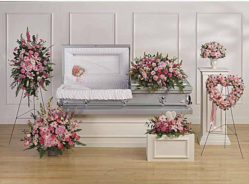 Pink floral funeral casket spray with matching standing wreaths and arrangements
