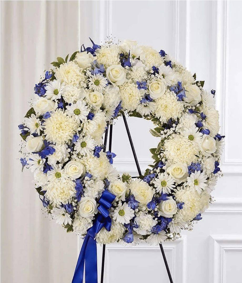 White and blue floral wreath on a stand with a blue ribbon