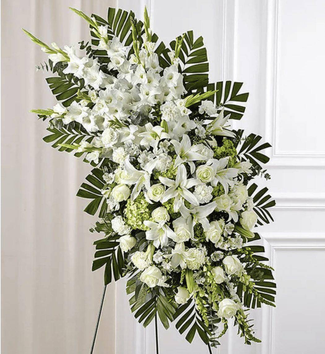 White floral standing spray with lilies and roses on a display easel