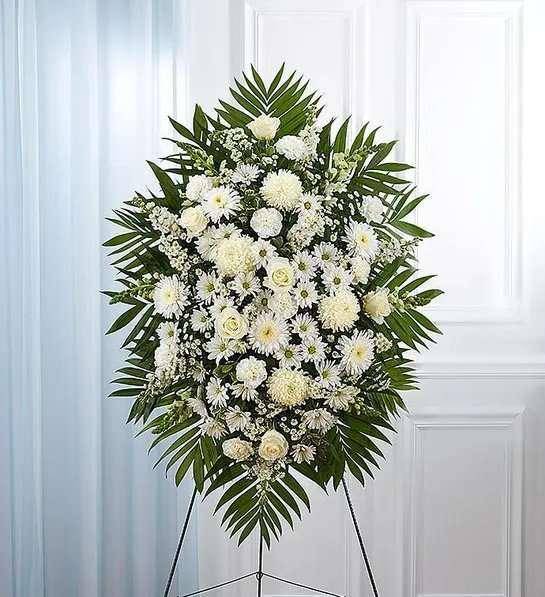 White funeral spray on an easel with palm fronds