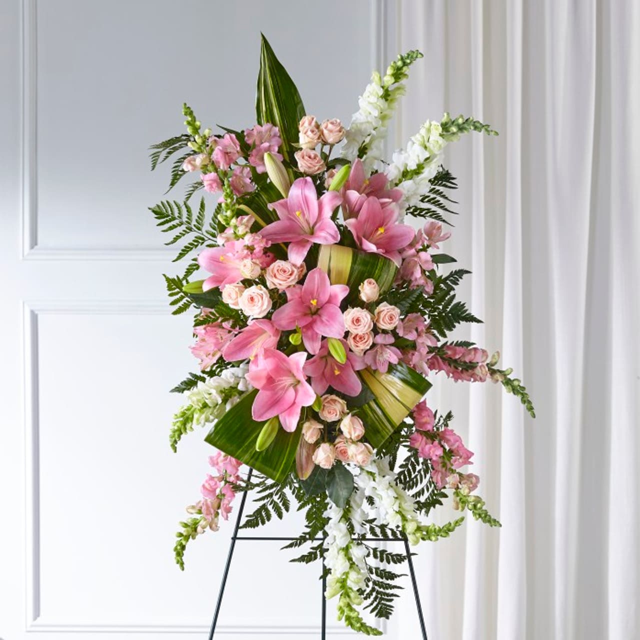 Elegance Embrace Standing Spray - Our Elegant Embrace™ Standing Spray shares the warmth and comfort your loved ones need during this difficult time through each blushing bloom. A local florist beautifully combines lilies, spray roses and snapdragons with greens to express your heartfelt love.Spray is approximately 38"L x 22"W.